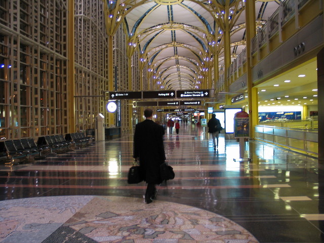 Muž v čiernom kabáte kráča po letisku, batožina, businessman