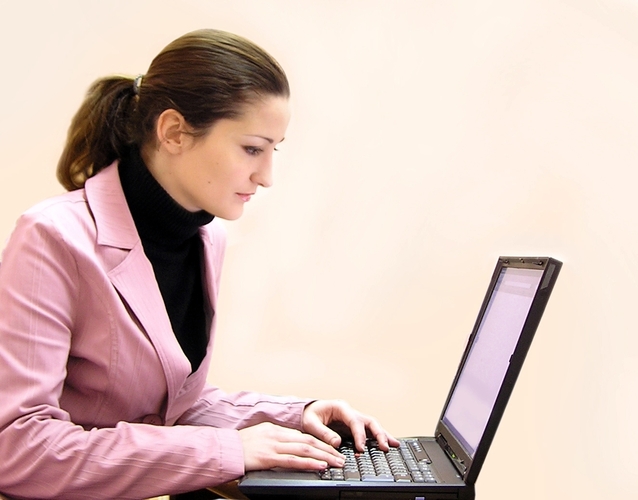 Žena v ružovom obleku pracuje s notebookom.jpg